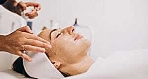 Cosmetologist cleaning face of a woman in a beauty salon